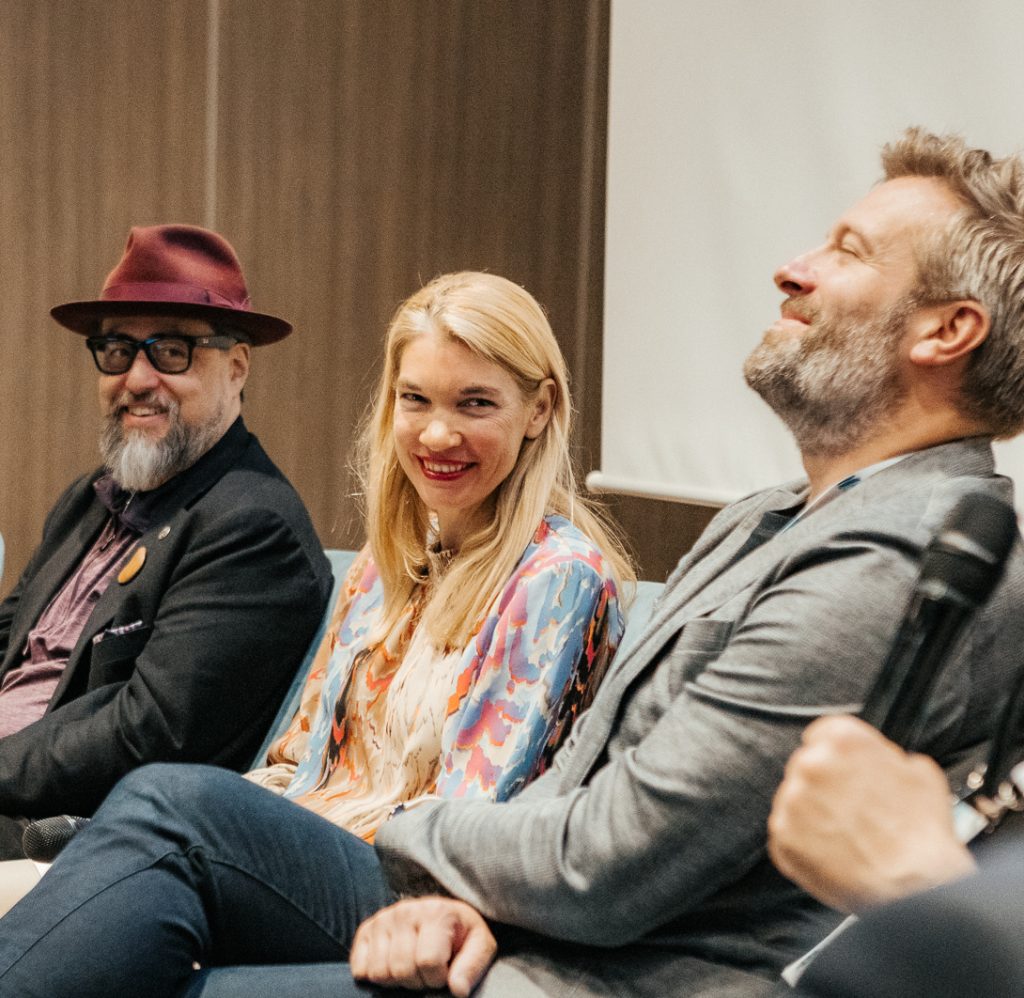 Susanne Schorsch speaking on a panel at the 0100 conference. A panel of 5 speakers laughing and smiling while they discuss deep tech growth funding.