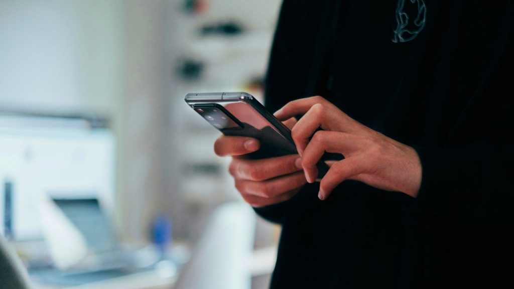 A photo of a ladies hands whilst she is using a smartphone to represent the consumer lending platform created by Creditas.