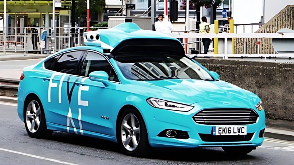 A London street scene which features the FiveAI test autonomous vehicle, which is a Ford Mondeo with sensors and other equipment on its roof. The car is followed by a red double decker bus.
