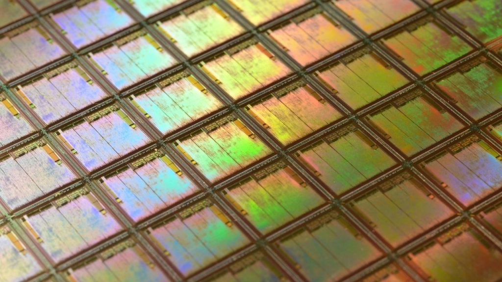 a macro photo of a metallic circuit board showing a grid of semiconductor chips.