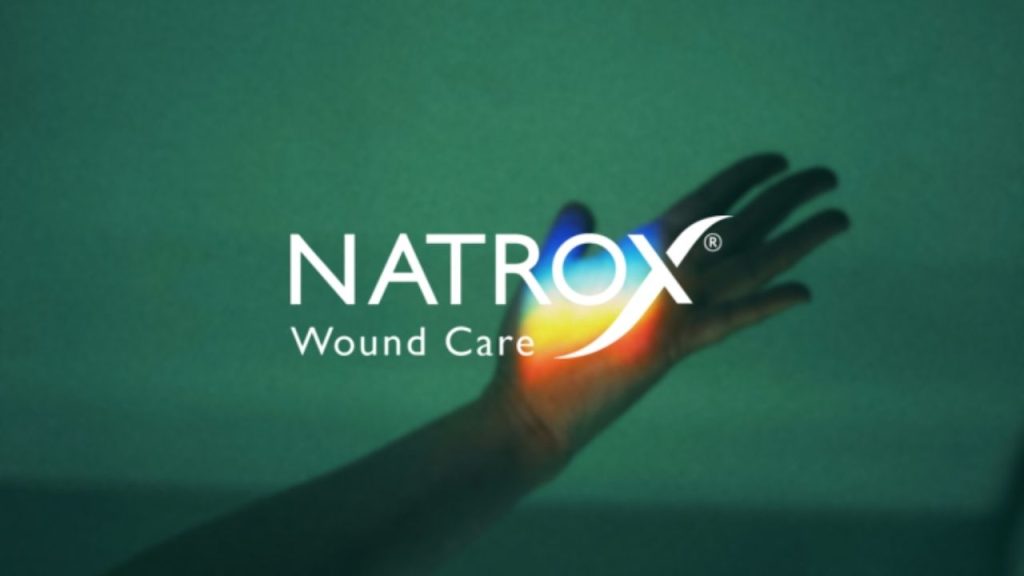 Natrox company logo overlaid on a photo of a hand with a rainbow of light projected on to the palm.