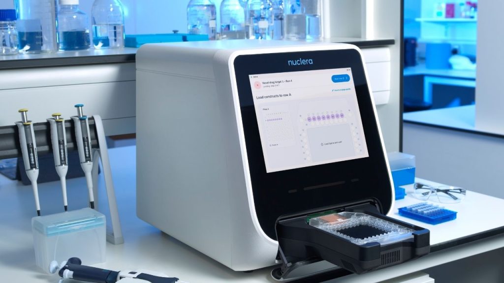 a laboratory photo showing Nuclera's eProtein Discovery system for rapid, automated protein production. The device has a large screen on the front and a tray which pops out from beneath for dispensing the created protein.