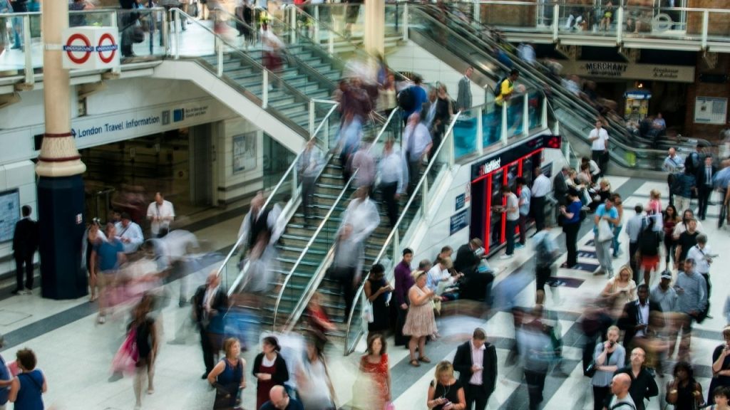 A long-exposure shot of a London station scene used to represent the fast-paced retail environment which Openbravo created point of sale software for. The image includes a lot of people moving around, up and down steps and congregating in groups in an open space, which includes shops.