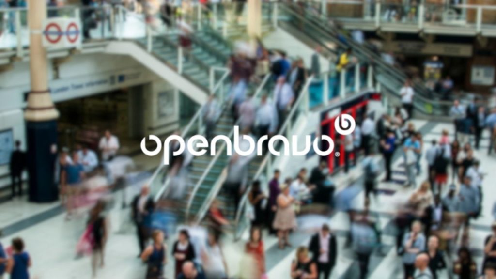 Openbravo company logo overlaid on a long-exposure shot of a London station scene used to represent the fast-paced retail environment which Openbravo created point of sale software for. The image includes a lot of people moving around, up and down steps and congregating in groups in an open space, which includes shops.