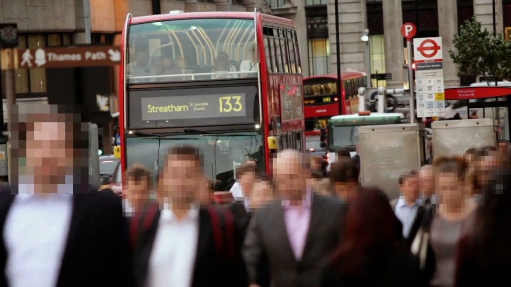 a crowd of people walking down a London street with their faces blurred using Pimloc's Secure Redact visual privacy platform.