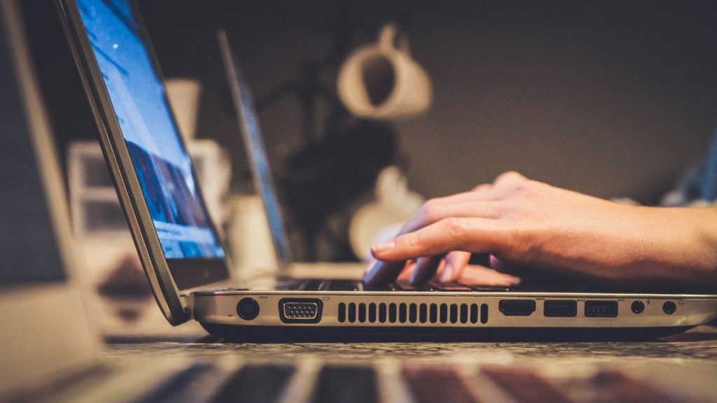 a side on photo of hands on a laptop keyboard to represent the online merchants which Ravelin software protects.