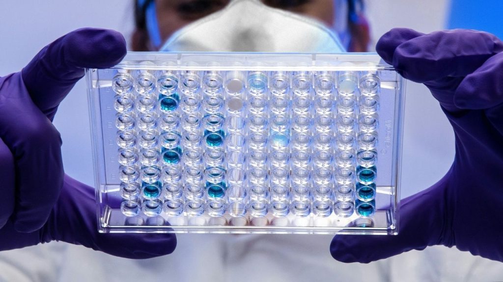 a lab technician's hands holding a DNA test tray containing samples representing the technology developed by Solexa which made this possible.