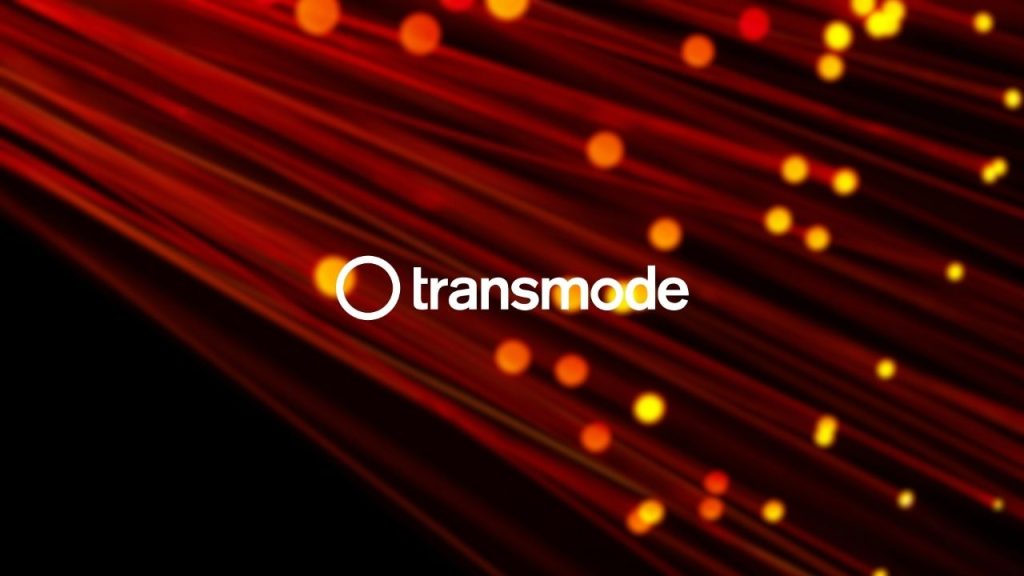 transmode company logo overlaid on a a close-up image of optical fibres which chows light shining through the tips of each fibre-optic cable. This is representative of the light-switching technology developed by Transdmode for telecoms operators.