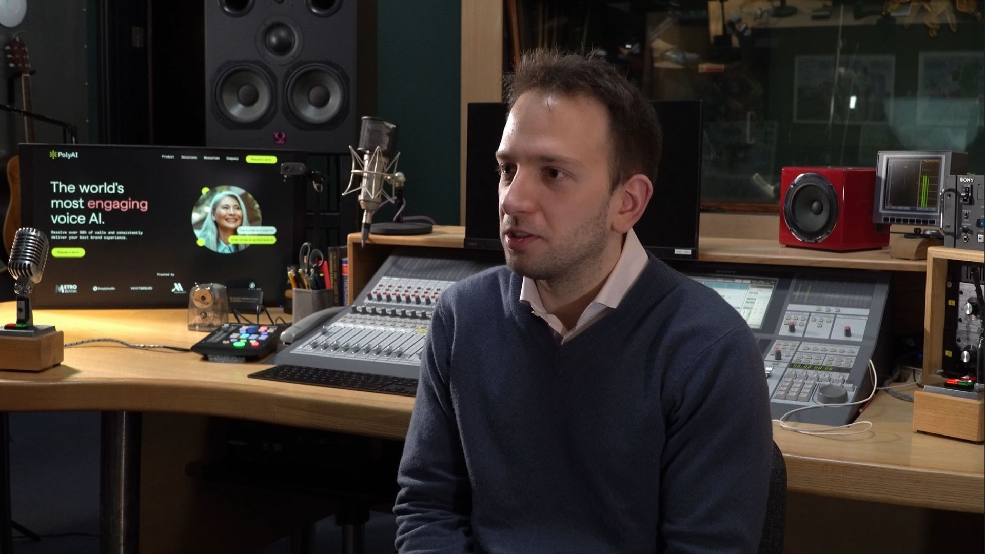 Nikola Mrkšić, co-founder and CEO of PolyAI, sitting on a chair in a studio setting whil discussing his entrepreneurial journey into creating Voice AI for customer service.