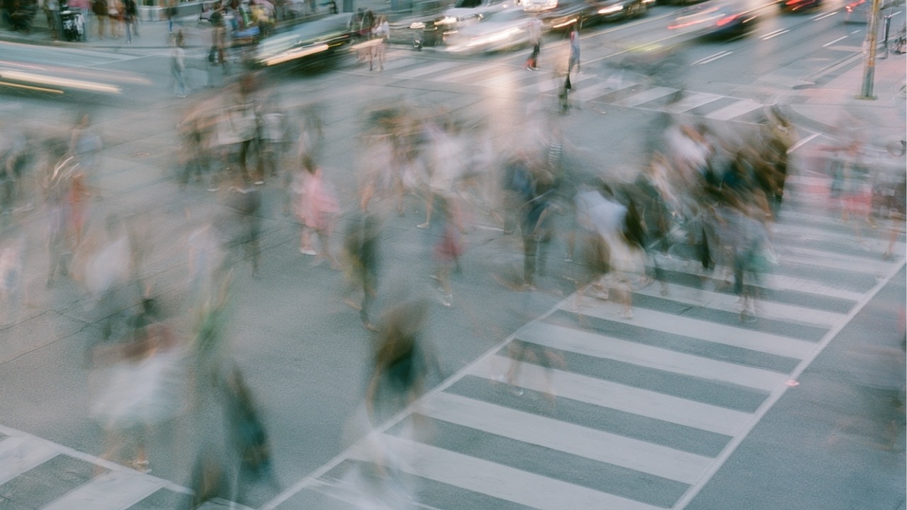 An AI-generated image of a busy intersection which has a motion blur of people crossing it.
