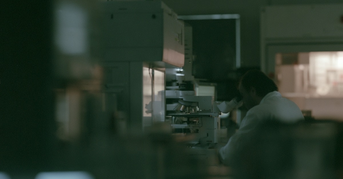 An AI-generated image showing a scientist using a microscope in a clinical environment.