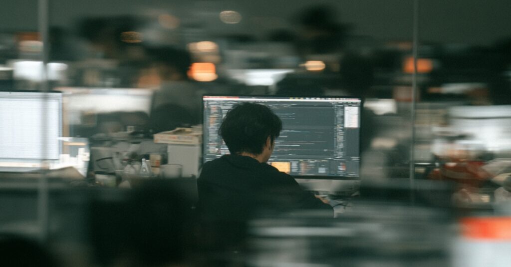 An AI-generated image of a developer sat at a computer screen in an office environment.
